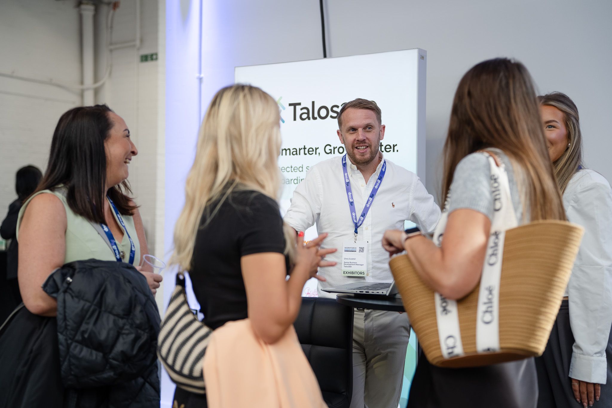 An exhibitor talking with visitors at their stand at WIE 2026