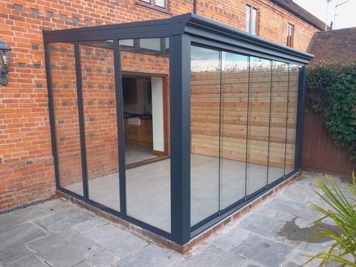 Pigato glass roof veranda garden room with fixed glass and sliding glass sides.