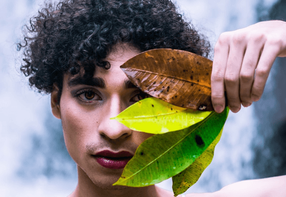 Man-wearing-make-up-holding-leaves