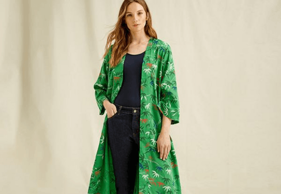 Woman standing wearing a green kimono with palm tree print