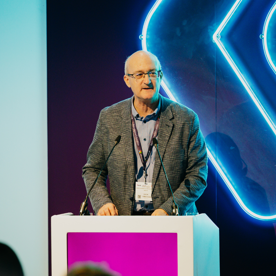 Perry Hobson presenting behind lectern with blue neon light behind him 