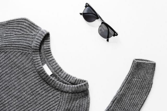 Grey jumper and black sunglasses on a white background