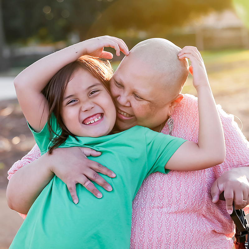woman sitting in a wheelchair hugging a girl