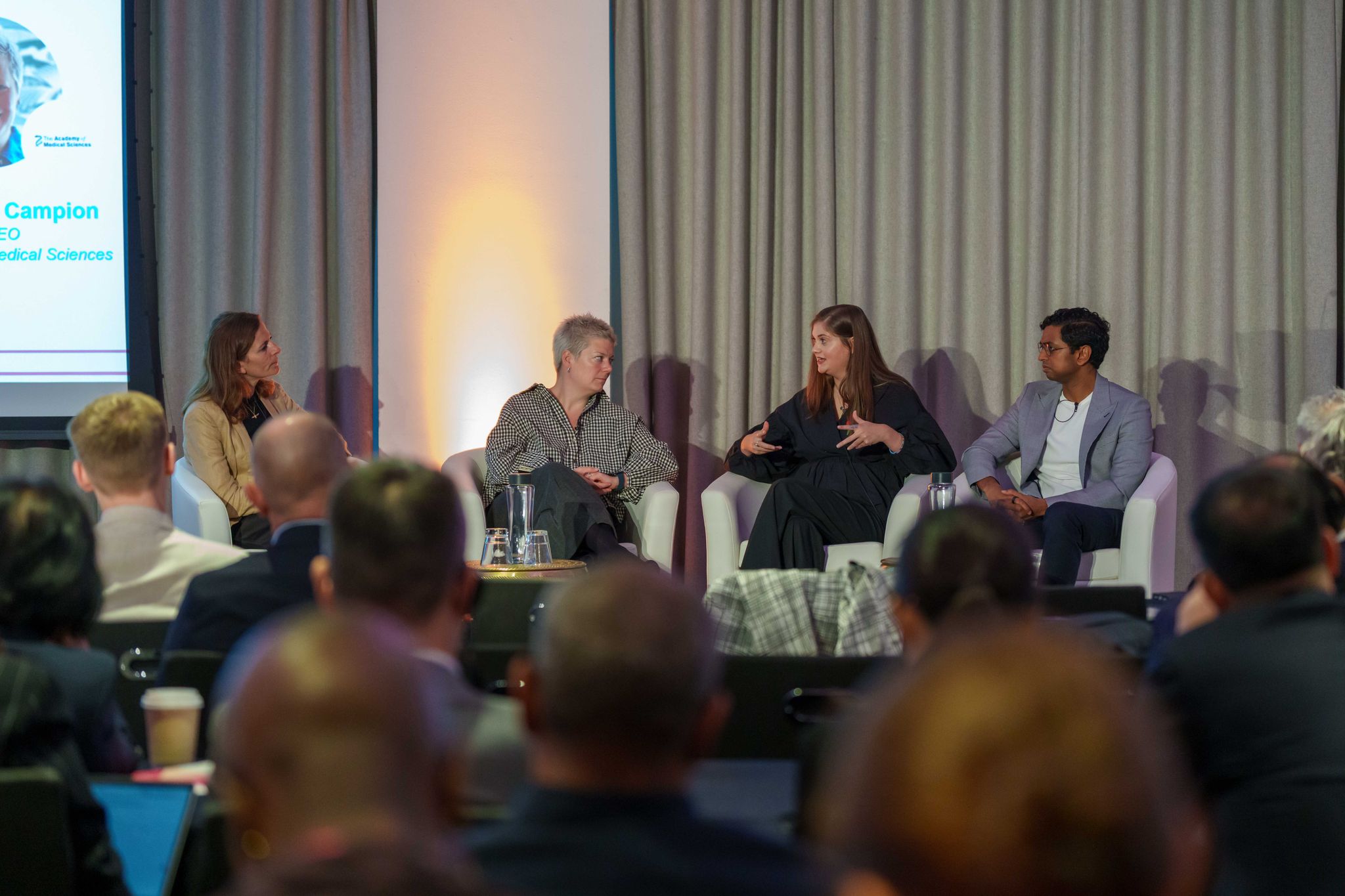 Panel of experts sitting on a stage with audience listening