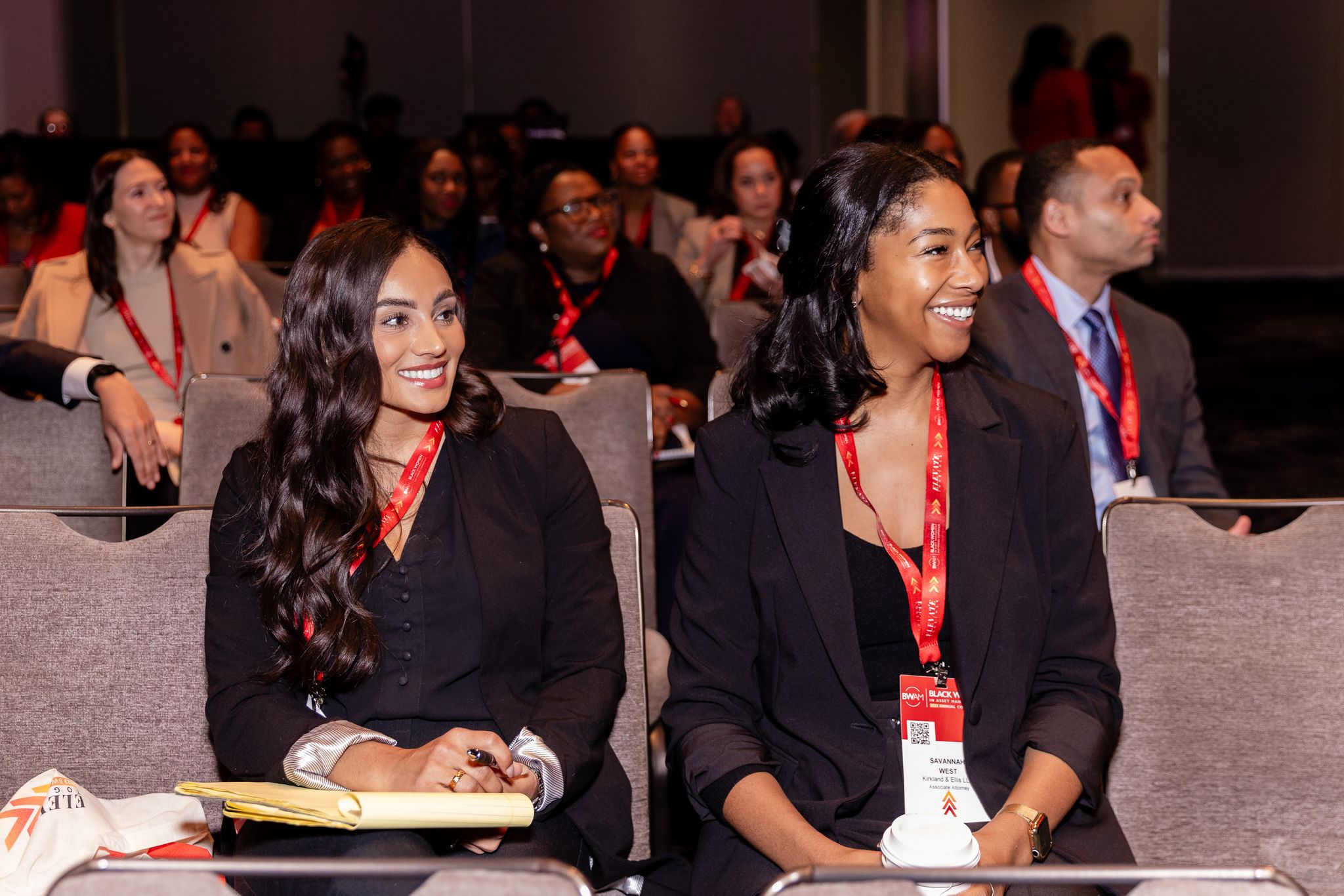 Two women in the audience listening and smiling 