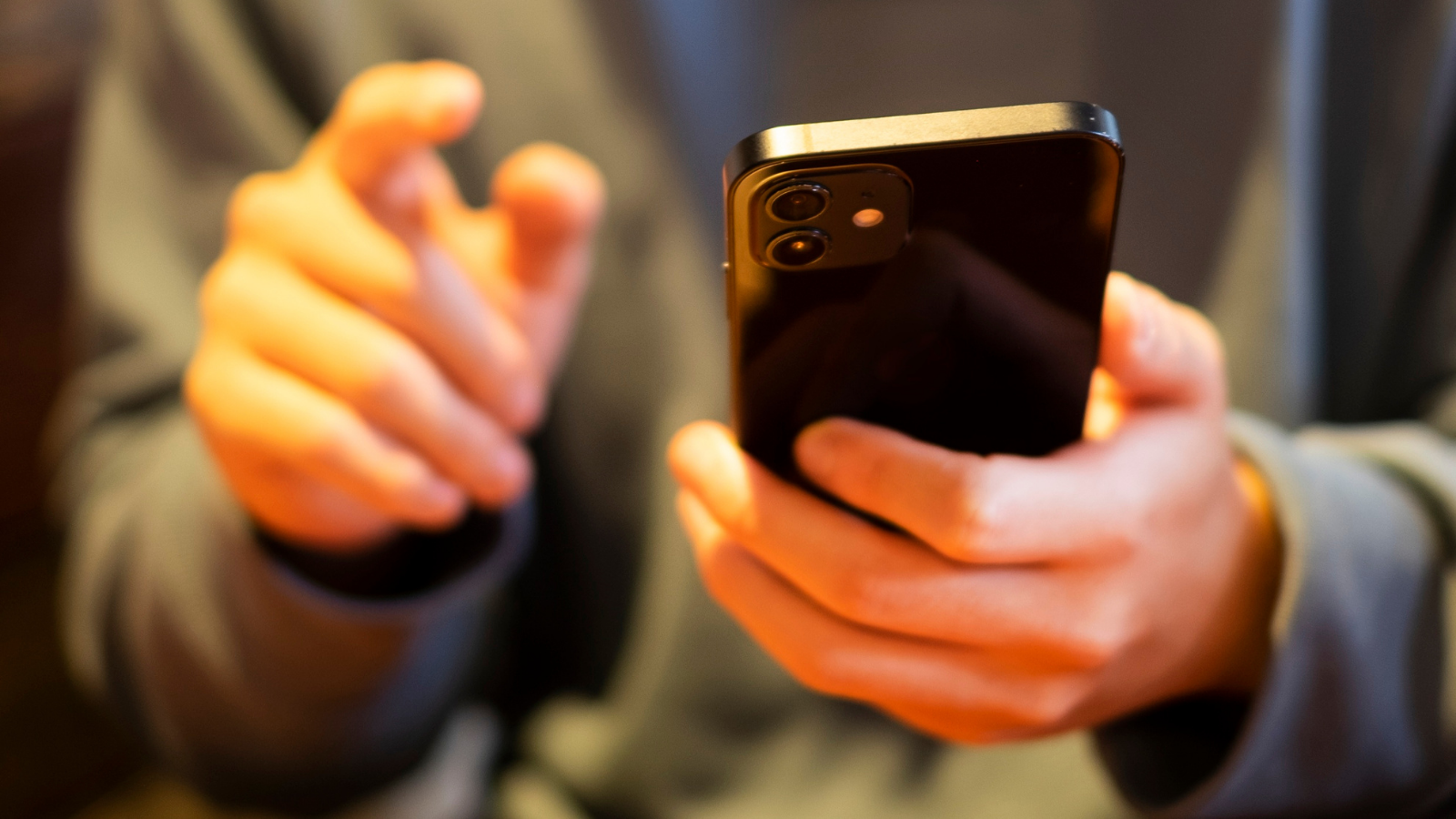 a person holding a smart phone, the person is blurred in the background and the phone is in the foreground