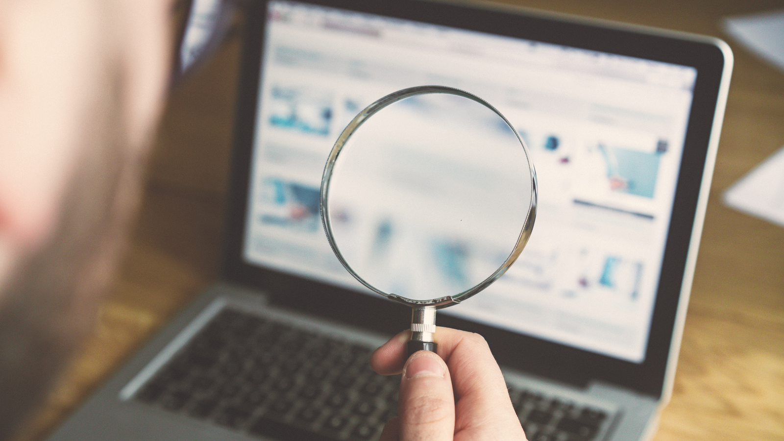 somebody holding a magnifying glass over a laptop