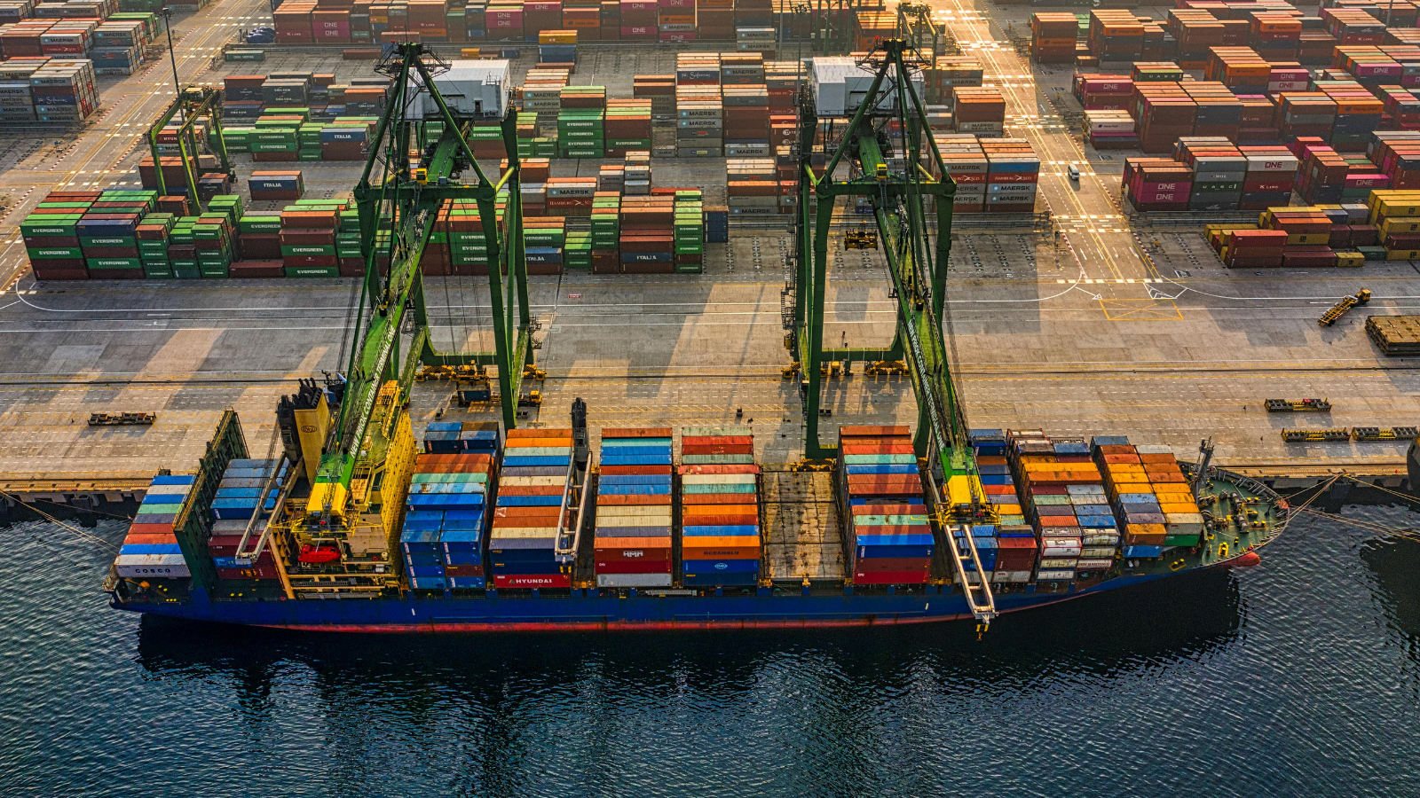 Cargo ship being unloaded at a US shipping port, highlighting global trade, logistics infrastructure, and e-commerce supply chain investment