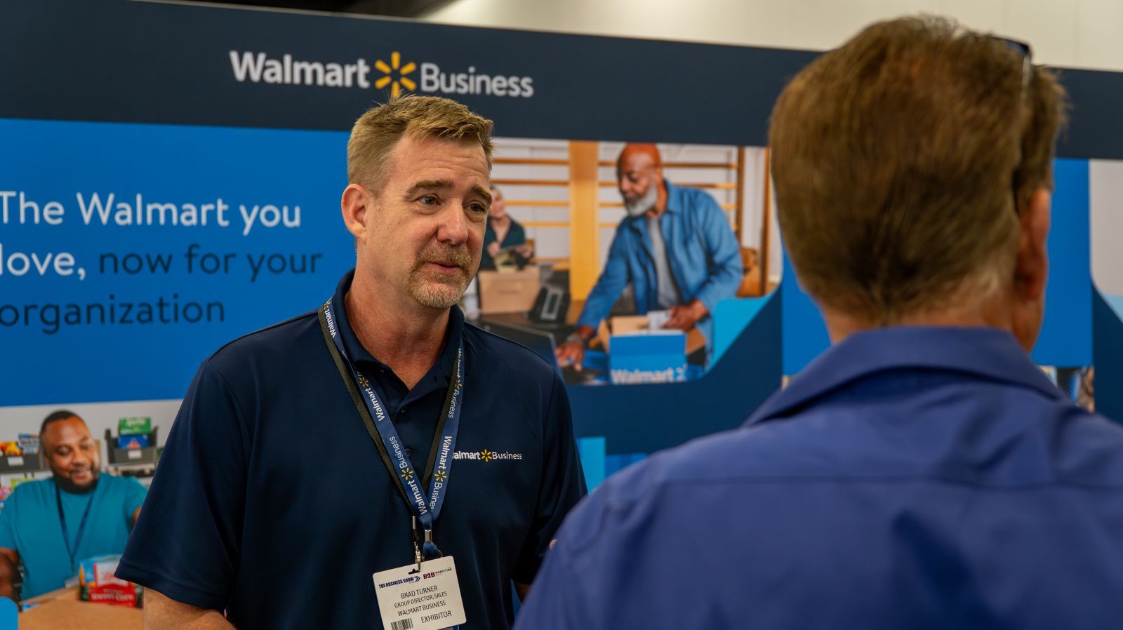 A Walmart worker speaking to a trade show attendee