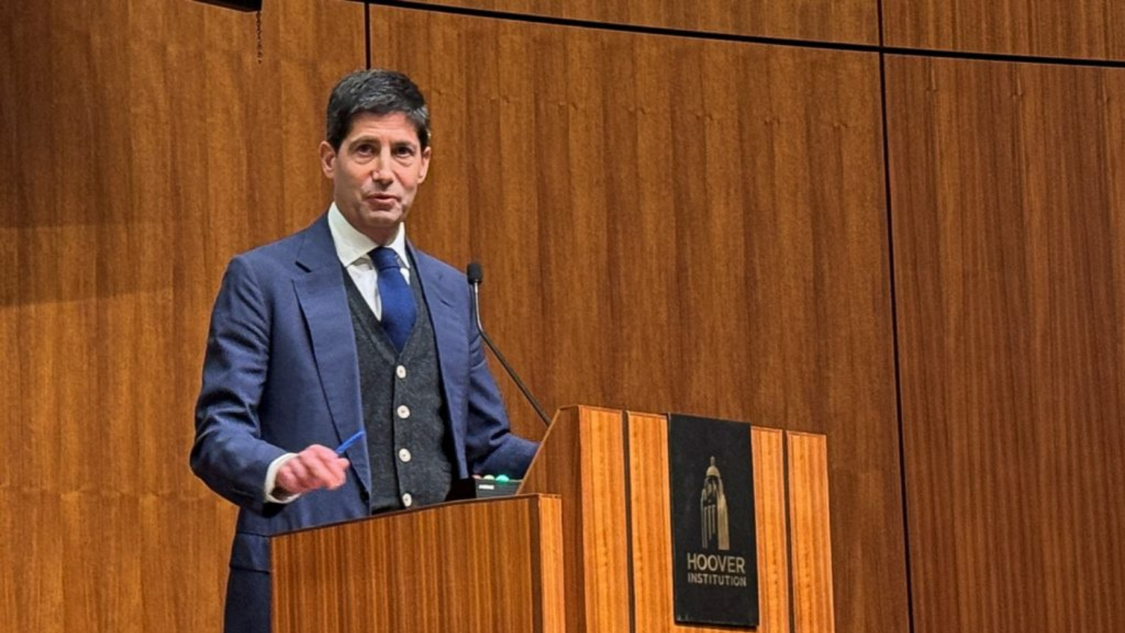 Man speaking at a podium at the Hoover Institution, representing Federal Reserve leadership and US monetary policy discussions