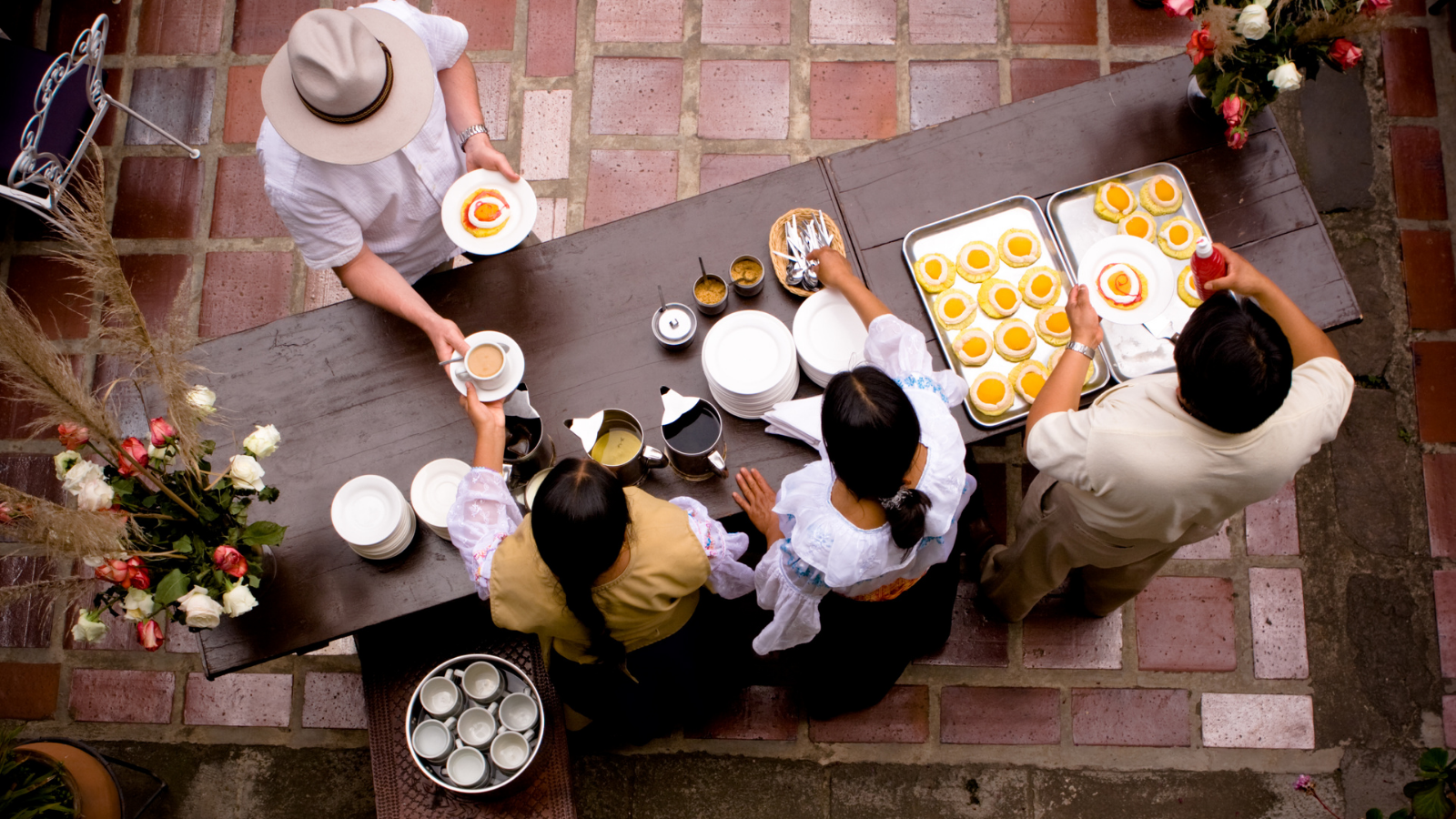 a top down shot of a group of people eating and drinking and being served by a waiter