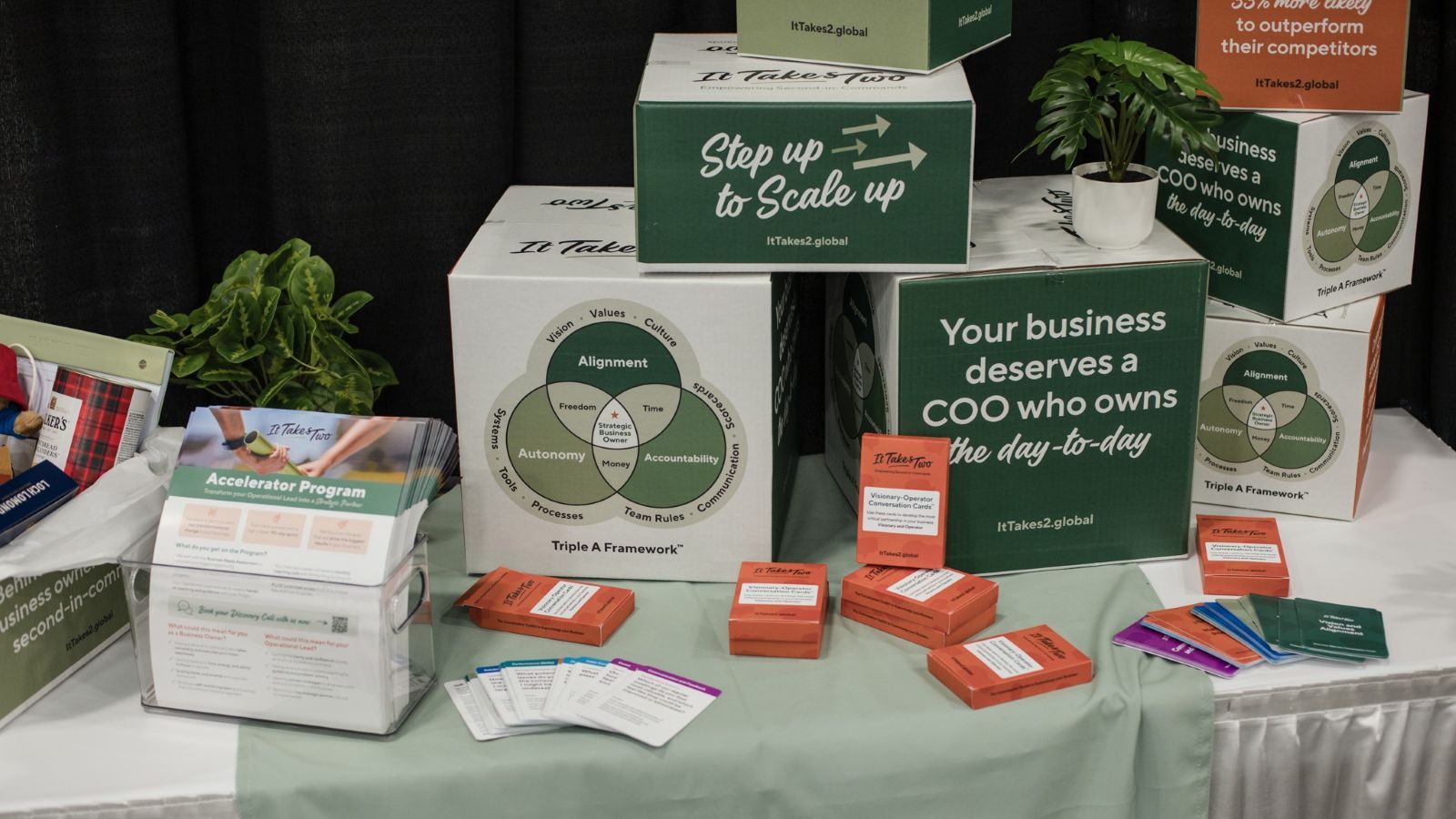 An image of a company's booth at The Business Show, with merchandise, business cards, and a display