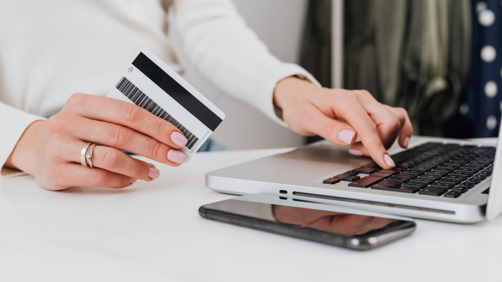 A stock image of a person holding a credit card in front of a computer