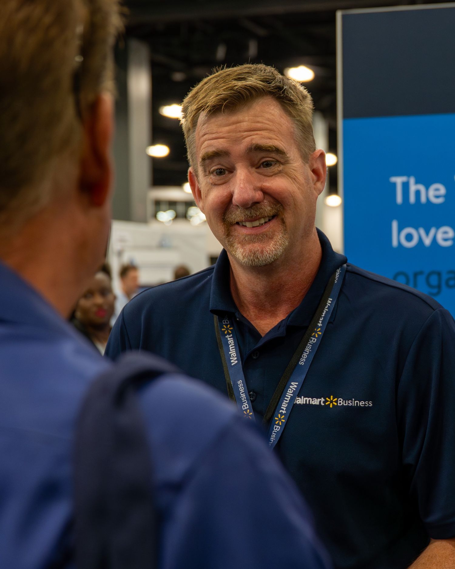 A man wearing a walmart business uniform talking with another man at the Business Show Miami.