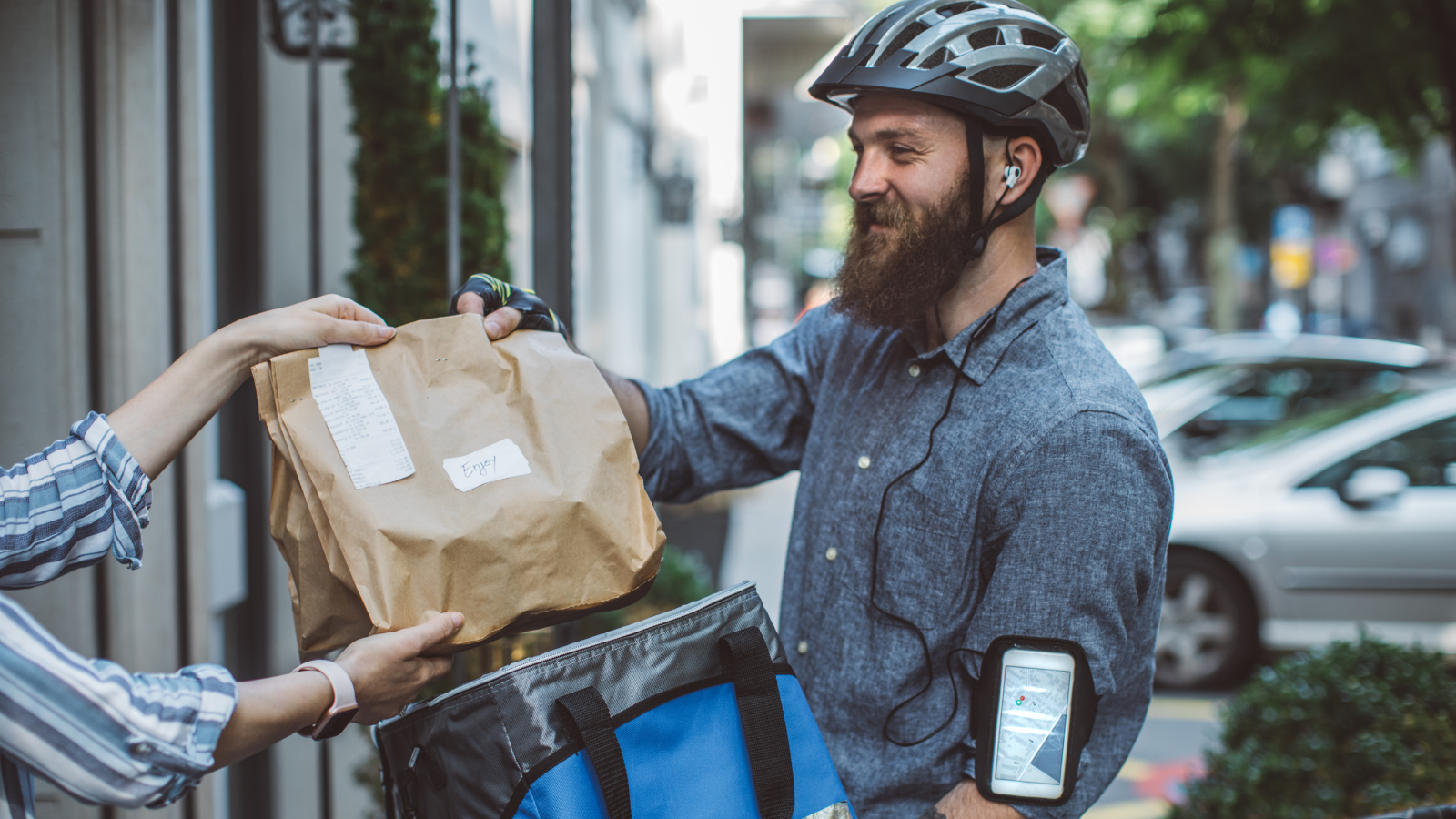 Delivery driver handing over a packaged order to a customer, illustrating instant ecommerce and last-mile delivery service