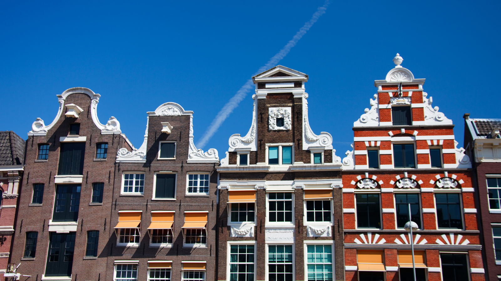 Traditional Dutch canal houses with ornate gabled facades in Amsterdam, Netherlands.