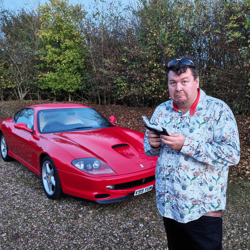 YouTuber JayEmm holding an empty wallet next to a red Ferrari 550 Maranello