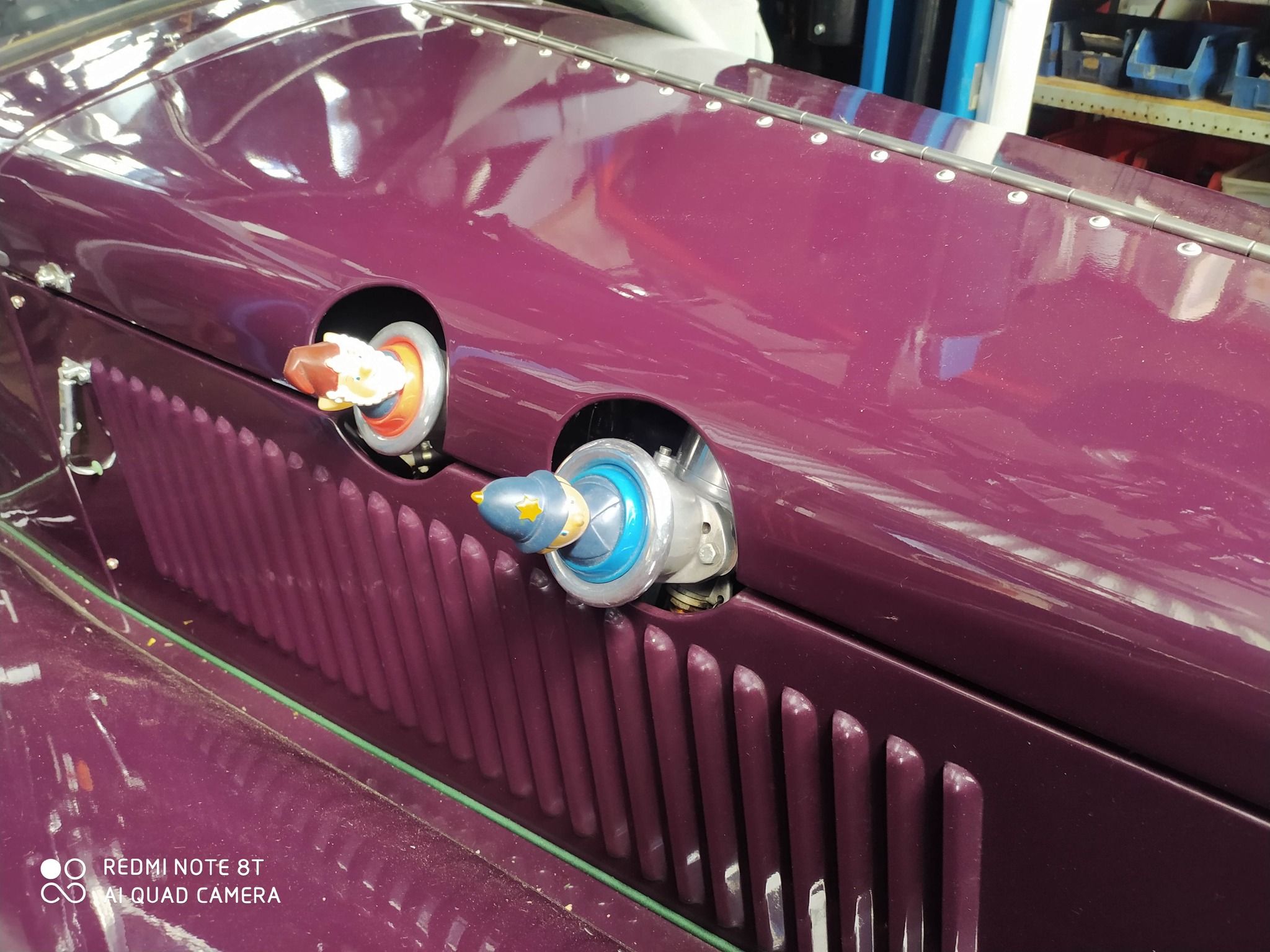 Close-up of the polished twin SU carburettors and bonnet detail on a purple Vincent MPH, a replica 1930s Riley classic car.