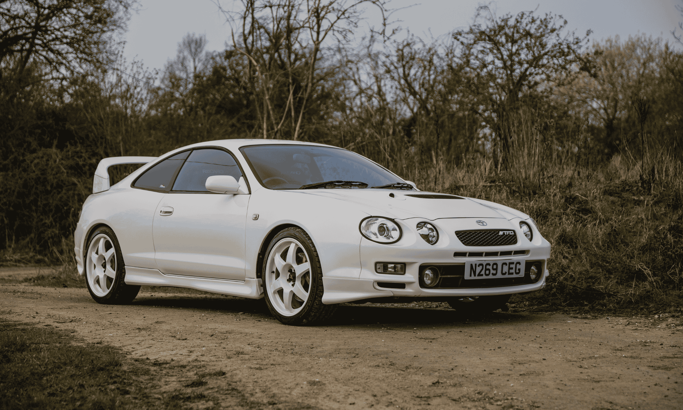 White Toyota Celica GT-Four ST205 parked on a dirt track, featured on JayEmm on Cars
