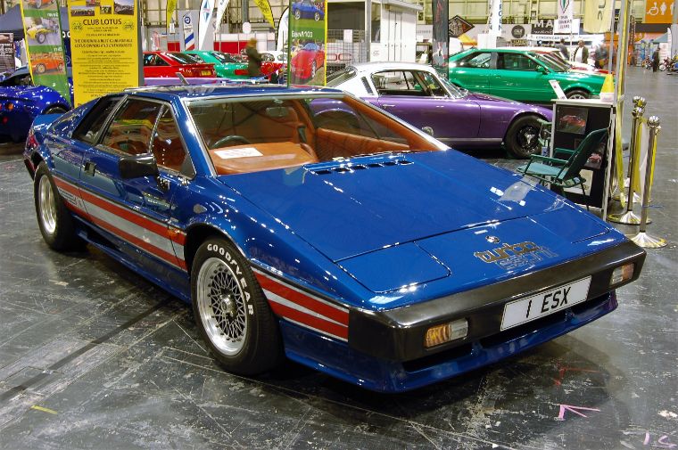 A blue Lotus Esprit Turbo classic sports car with red racing stripes at a car show.