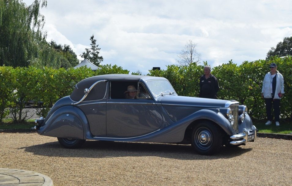 Dark grey 1950 Jaguar MkV Drophead Coupé convertible with two people standing nearby.