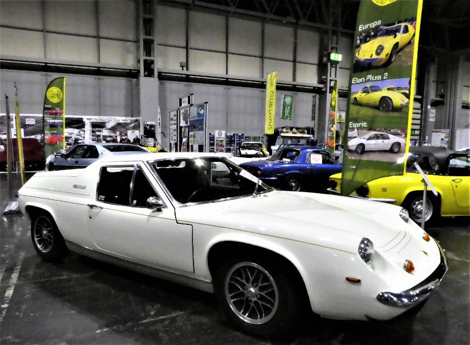 Classic white Lotus Europa vintage sports car on display at an indoor car show.
