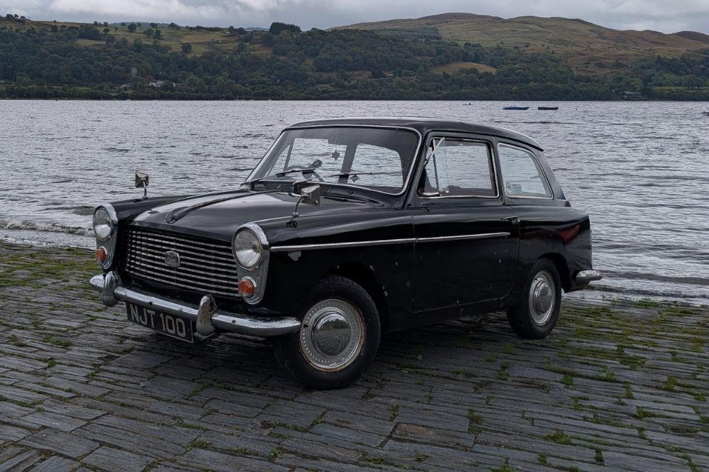 Classic black Austin A40 Farina parked on a slipway next to a lake, featured on Tasty Classics