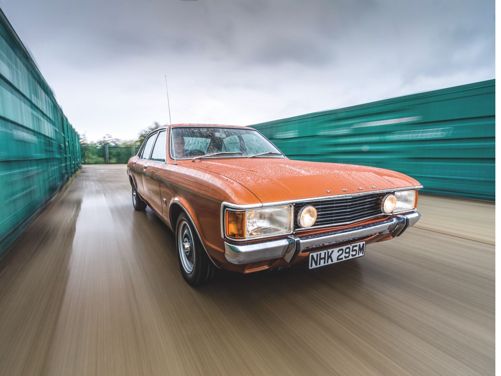 Vintage orange Ford Consul saloon car in a motion shot on a wet road, famously used in the classic TV series The Sweeney.
