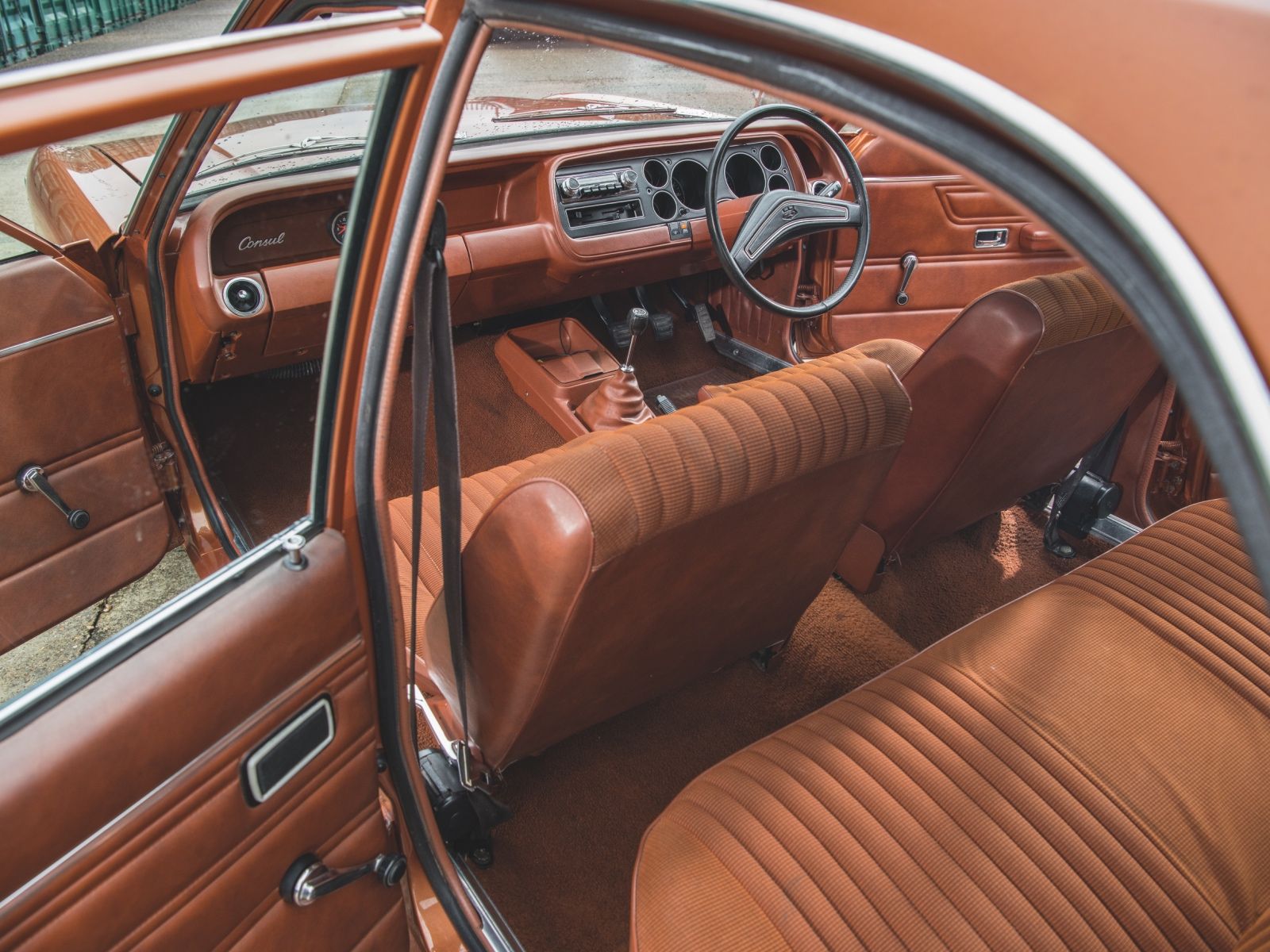 Brown leather interior of a vintage Ford Consul GT, showing the classic 1970s dashboard and ribbed seats.
