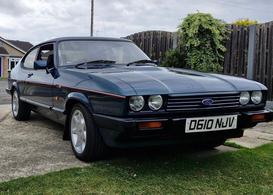 Classic dark blue Ford Capri 280 Brooklands coupe parked on a residential driveway featuring quad headlights and alloy wheels