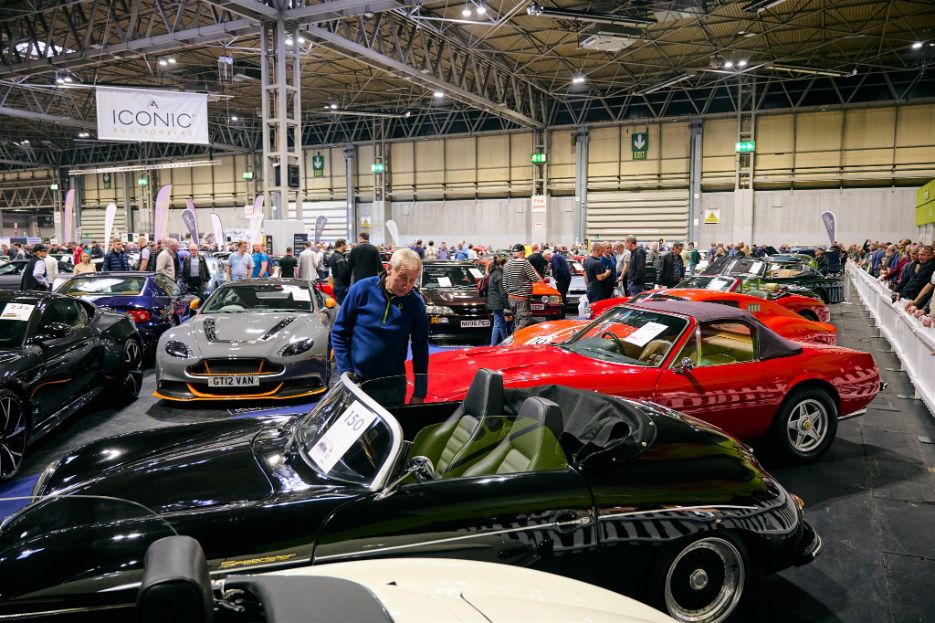 Man admiring a black Porsche 356 Speedster at the Iconic Auctioneers classic car show.