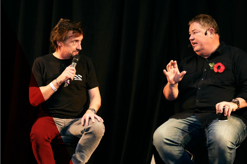Mike Brewer and Auto Alex in a live interview at the 'Meet the Experts' Theatre during the Classic Motor Show, drawing a large crowd of automotive enthusiasts.