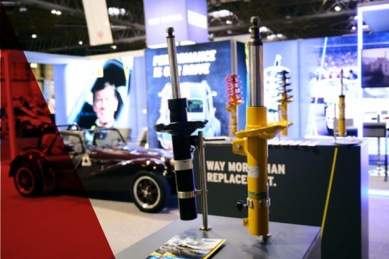 Performance car parts by Bilstein, including display shocks and a classic Caterham Seven style sports car, at the Classic Motor Show.