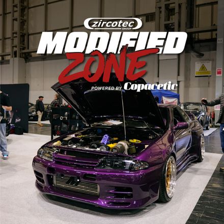 Purple modified Nissan Skyline GT-R with open bonnet inside the NEC exhibition hall, featuring the Zircotec Modified Zone powered by Copacetic logo overlay for the Classic Motor Show.