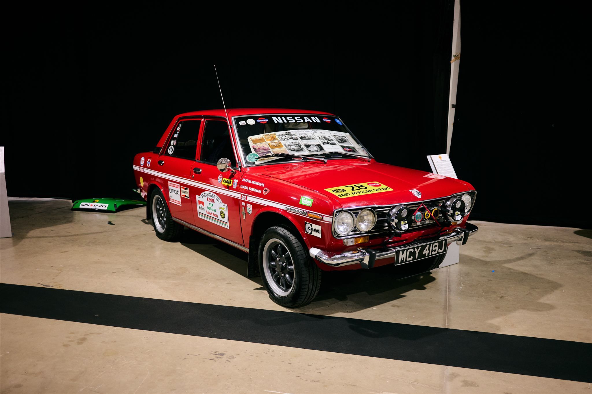 A classic red Datsun 1600 SSS East African Safari rally car, number 28, on display at the Pride of the Paddock awards.