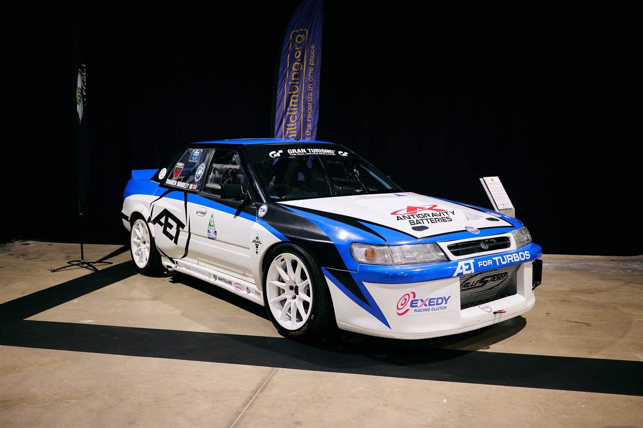 Side profile of a Subaru Legacy time attack car showing white racing wheels and performance aero kit.