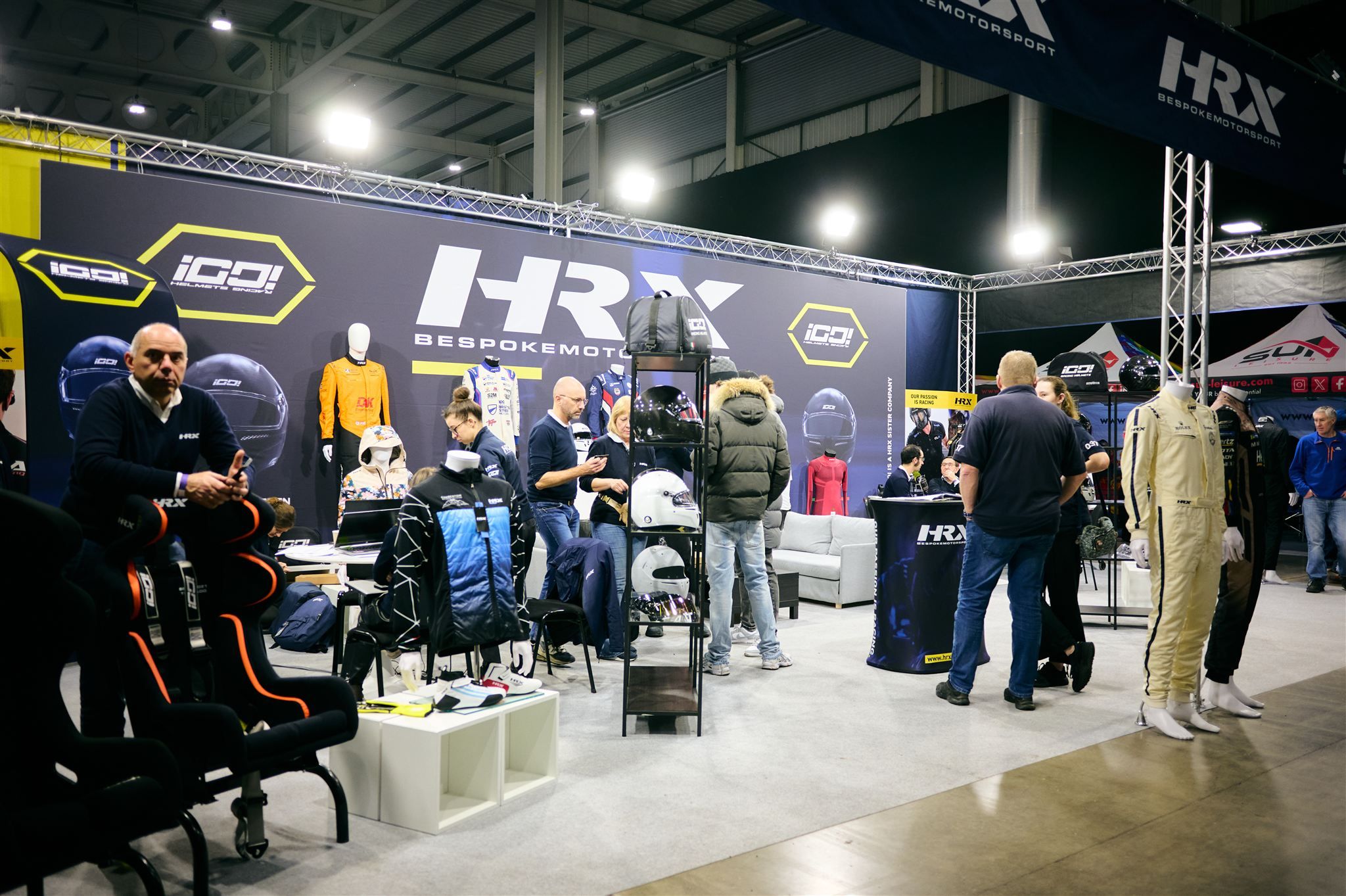 HRX Bespoke Motorsport exhibition stand featuring custom racing suits and helmets.