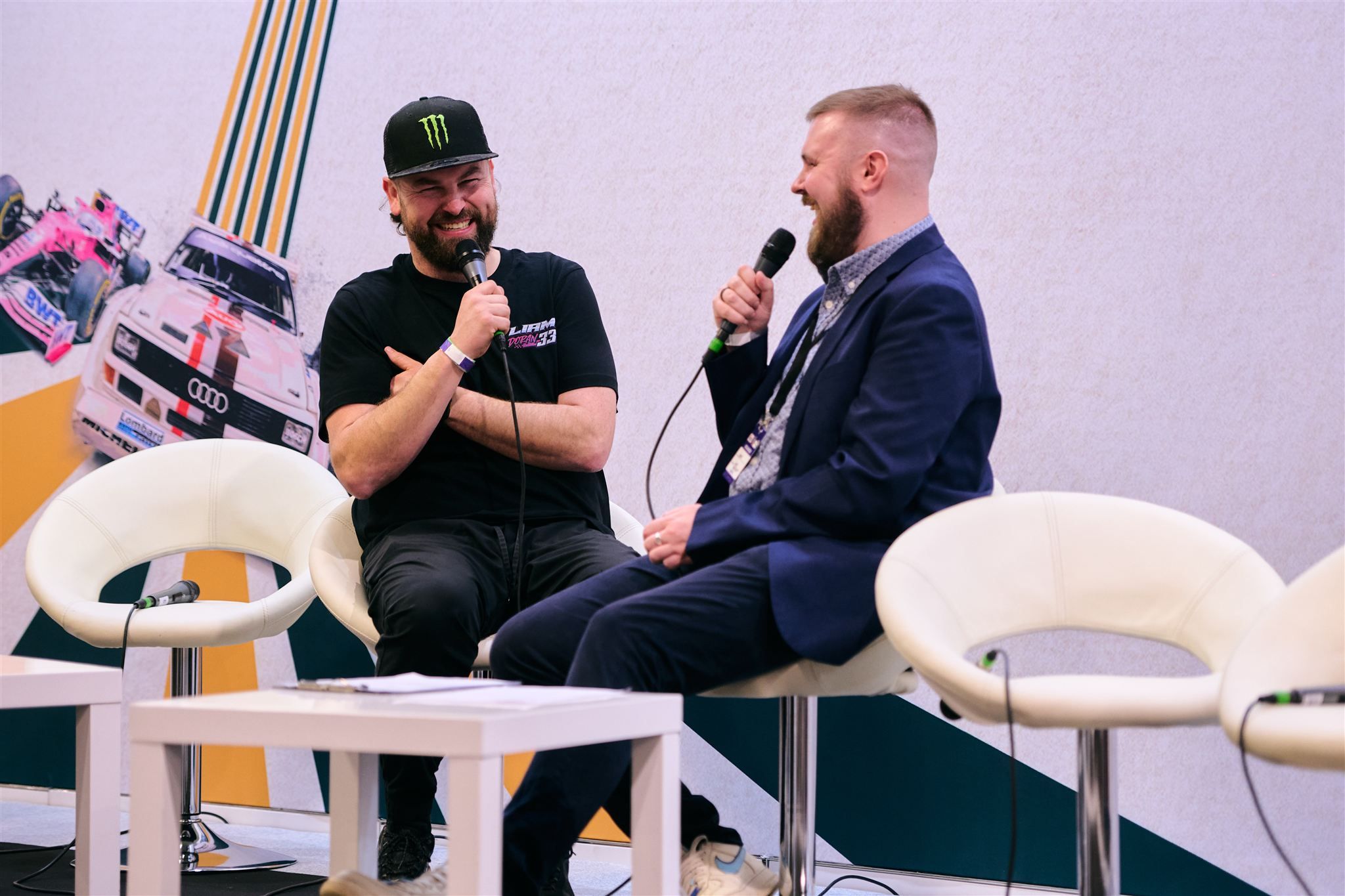 Rallycross driver Liam Doran in a Monster Energy hat laughing during an on-stage interview.