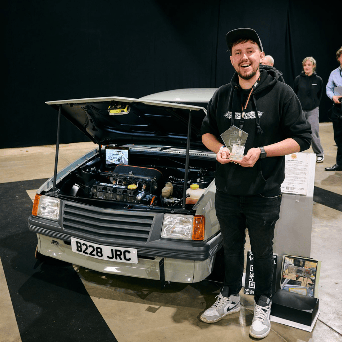 Modified grey Vauxhall Nova with B228 JRC plates and exposed engine bay on display at a car show.