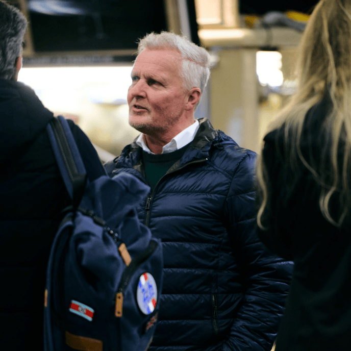 F1 legend Johnny Herbert talking to attendees at a motorsport trade show.