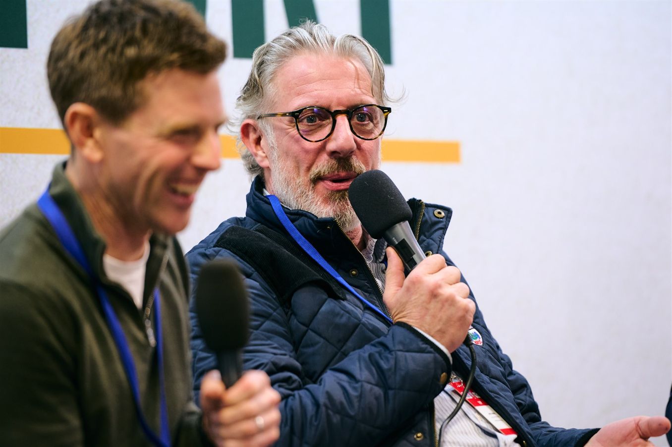 Jason Plato and Ant Anstead speaking into microphones during a live event panel discussion.
