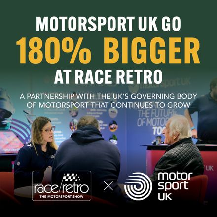 Motorsport UK booth display at Race Retro showing a representative speaking with visitors, with headline text reading 'Motorsport UK Go 180% Bigger at Race Retro'