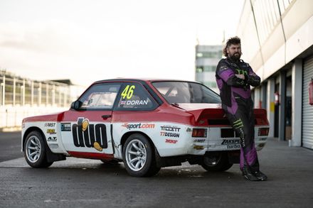 X Games gold medalist and world rallycross competitor Liam Doran next to a Ford Escort rally car.