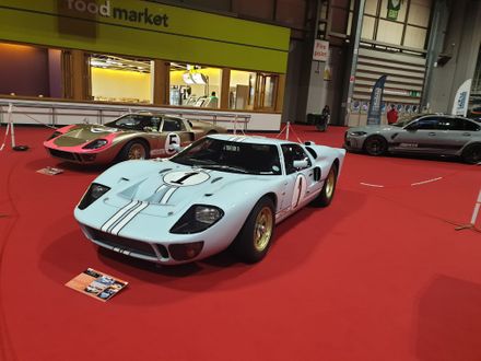 Ken Miles' #1 Ford GT40 Mk II race car from the 1966 Le Mans, displayed on a red carpet at an indoor car exhibition.
