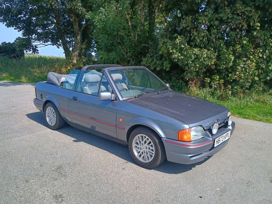 Metallic grey Ford Escort Mk4 Cabriolet parked on a rural roadside with the top down.