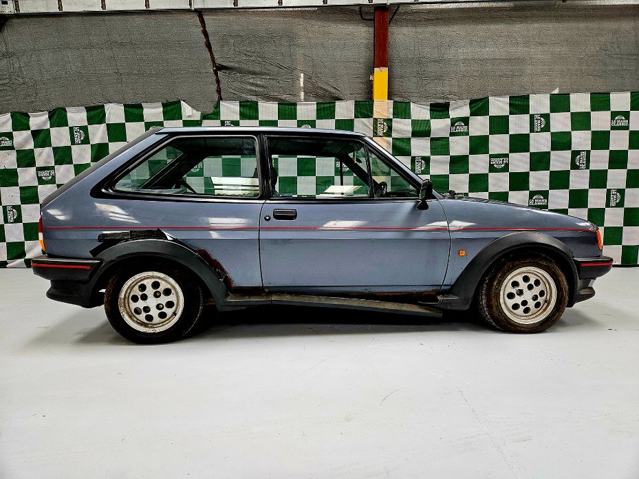 Blue 1987 Ford Fiesta XR2 Mk2 project car with rust on the wheel arches in a workshop setting.