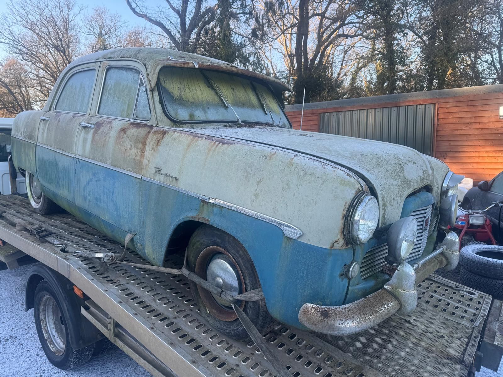 Rusty white Ford Zodiac Mk4 barn find project with significant body corrosion in a cluttered garage.
