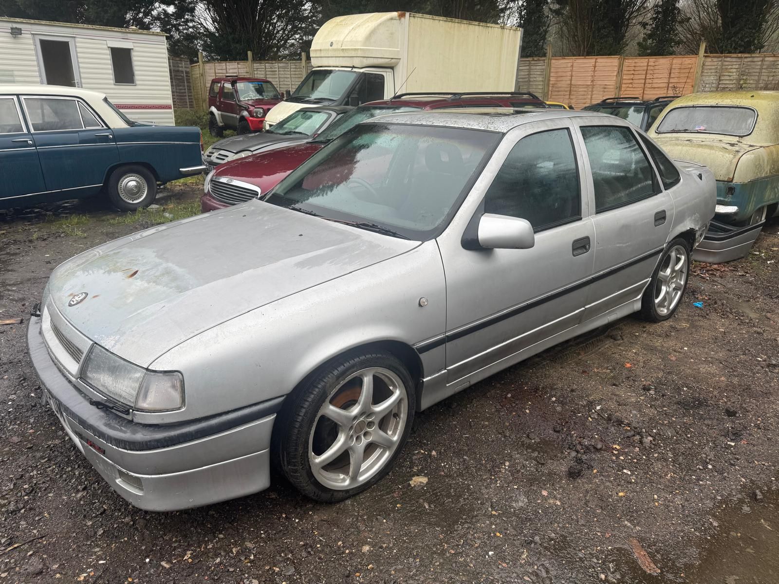 Gold Vauxhall Cavalier Mk2 saloon barn find with flat tires and a layer of dust in a brick building.
