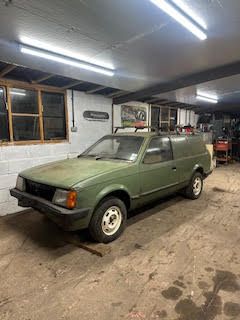 Green Vauxhall Astra Mk2 GTE-style van project car with aftermarket wheels in a storage unit.