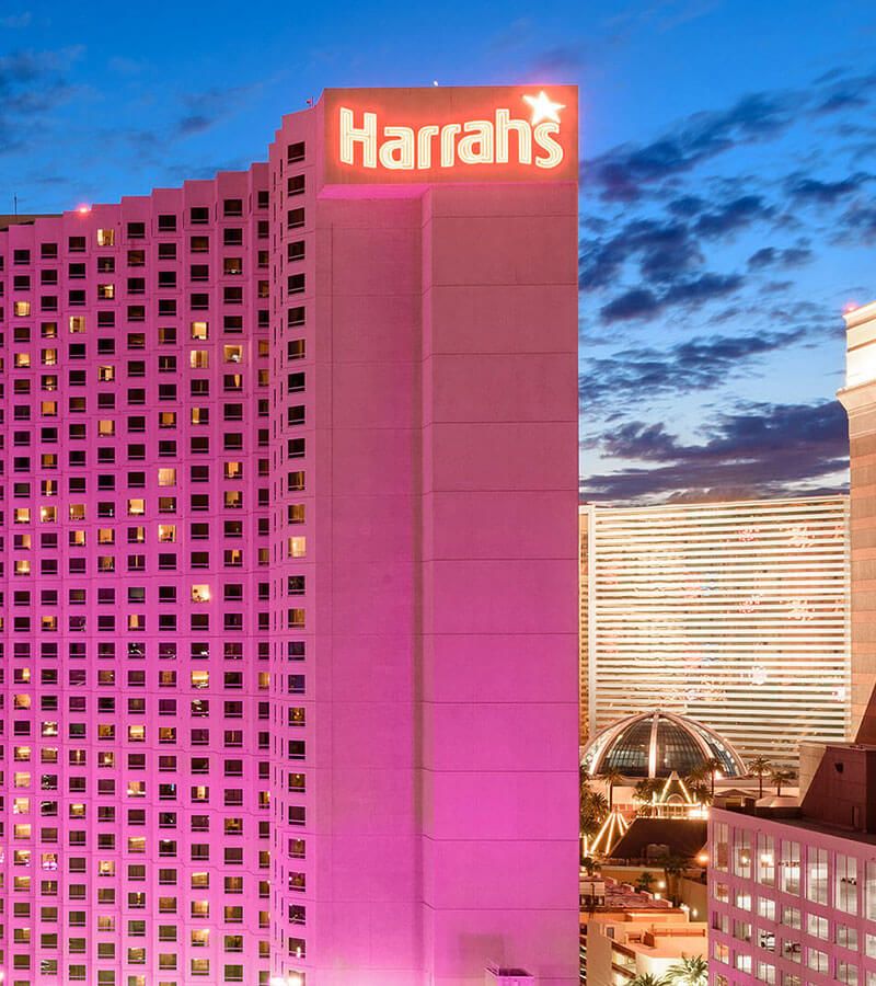 A picture of the Harrah's hotel lit up with purple lights at night.